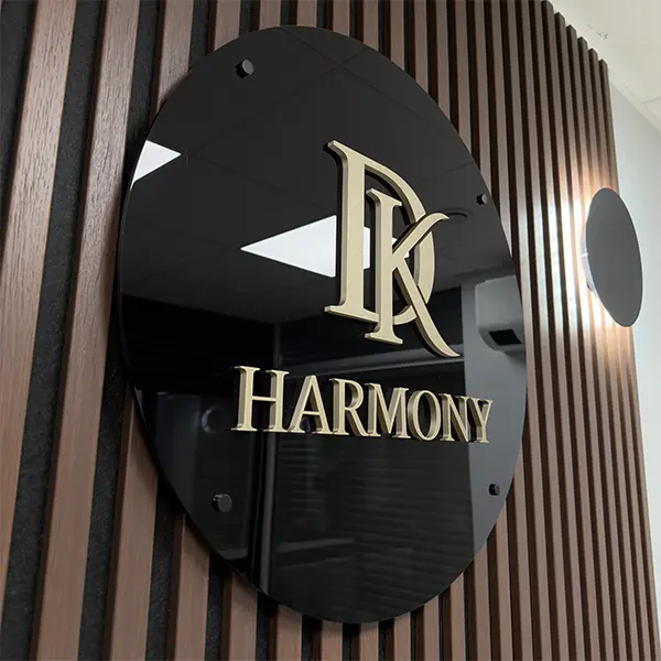 DK Harmony tūrinis logotipas ant juodo apvalaus akrilo